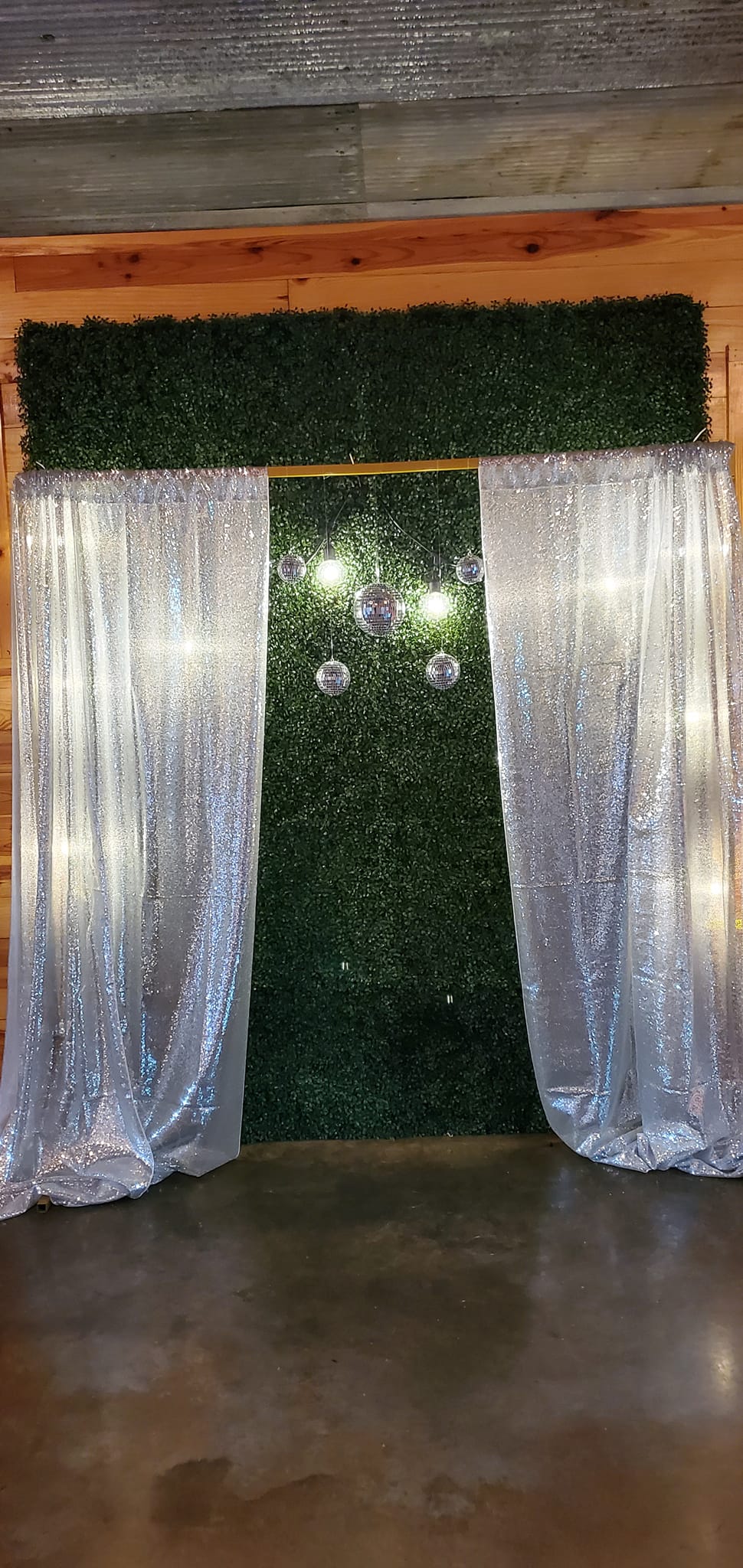 greenery wall photo backdrop with silver sparkly drapes and disco balls